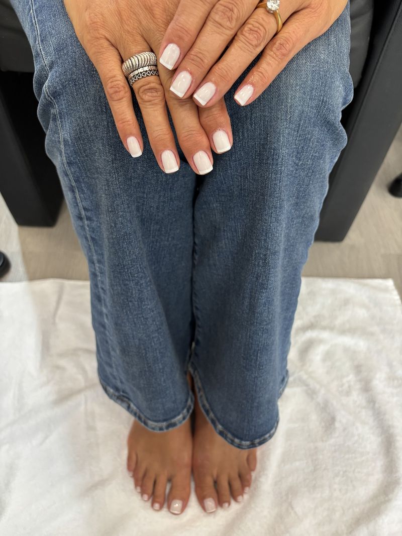 Cliente sentada com manicure e pedicure em branco leitoso a condizer